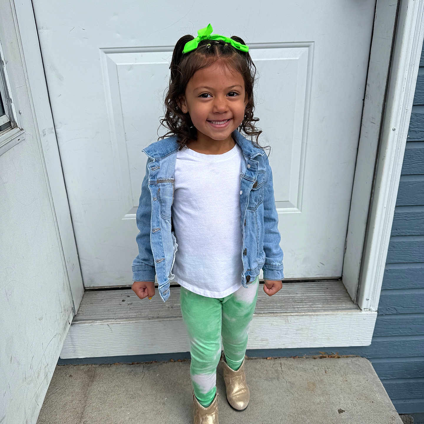 Emerlynn is registered to the contest to win money with this photo: casual_clothing, child, concrete_floor, curly_hair, denim_jacket, door, fashion, front_view, girl, gold_boots, green_bow, green_leggings, happy, outdoor, person, portrait, smiling, standing, white_shirt, young