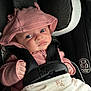 baby, infant, car_seat, pink_hood, clothing, blanket, safety_harness, face, hand, cute, child, newborn, seatbelt, car_interior, portrait, young_child, expression, looking_up, sitting, closeup