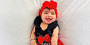 Taqdeer is registered to the contest to win money with this photo: baby, balloons, black_top, bracelets, child, cute, happy, indoors, infant, mickey_mouse, playful, plush_toy, portrait, red_dress, red_headband, sitting, smiling, toy, white_blanket, yellow_balloons