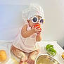 apron, baby, chef_hat, child, cooking, cute, flour, food, green_bell_pepper, indoor, kitchen, messy, mixing_bowl, plate, playful, sitting, sunglasses, table, tomato, whisk