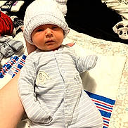 Lincoln is registered to the contest to win money with this photo: baby, infant, onesie, hat, knit_hat, elephant_patch, striped_clothing, blanket, hand, soft_lighting, baby_clothes, newborn, portrait, indoor, cute, sleepwear, child, person, cozy, resting