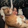 animal, arm, bed, casual, cat, comfort, cozy, cute, feline, human_face, indoor, lying_down, orange_cat, person, pet, pillow, relaxing, resting, smiling, white_cat
