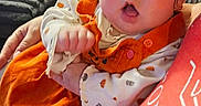 Calliope is registered to the contest to win money with this photo: baby, child, infant, portrait, wide_eyed, surprised, orange_outfit, bow, hair, face, eyes, open_mouth, sitting, cuddling, adult, sofa, cushions, window, blinds, indoor
