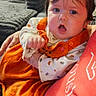baby, child, infant, portrait, wide_eyed, surprised, orange_outfit, bow, hair, face, eyes, open_mouth, sitting, cuddling, adult, sofa, cushions, window, blinds, indoor