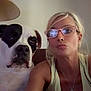 animal, blonde_hair, casual_clothing, closeup, companion, couch, dog, face, framed_picture, glasses, indoor, lamp, living_room, necklace, pet, portrait, relaxed, seated, selfie, woman