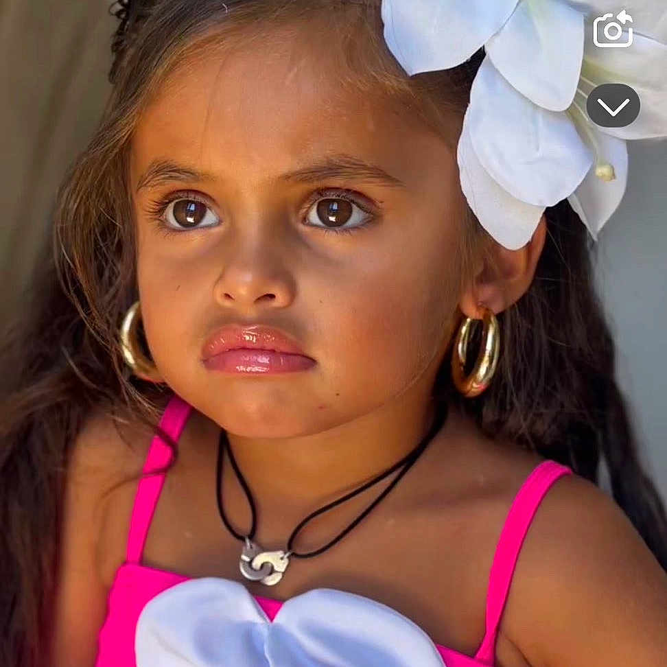 Ancana participe au concours pour gagner de l'argent avec cette photo : accessory, brown_eyes, child, close_up, cute, earrings, expression, fashion, flower_hairpiece, girl, glossy_lips, hair, necklace, pink_dress, portrait, studio_light, stylish, summer, tanned_skin, white_flower