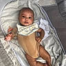 Cairo is registered to the contest to win money with this photo: baby, infant, onesie, bib, blanket, bassinet, pacifier, soft_fabric, cute, portrait, child, laying_down, indoors, clothing, face, skin, head, hand, foot, comfort