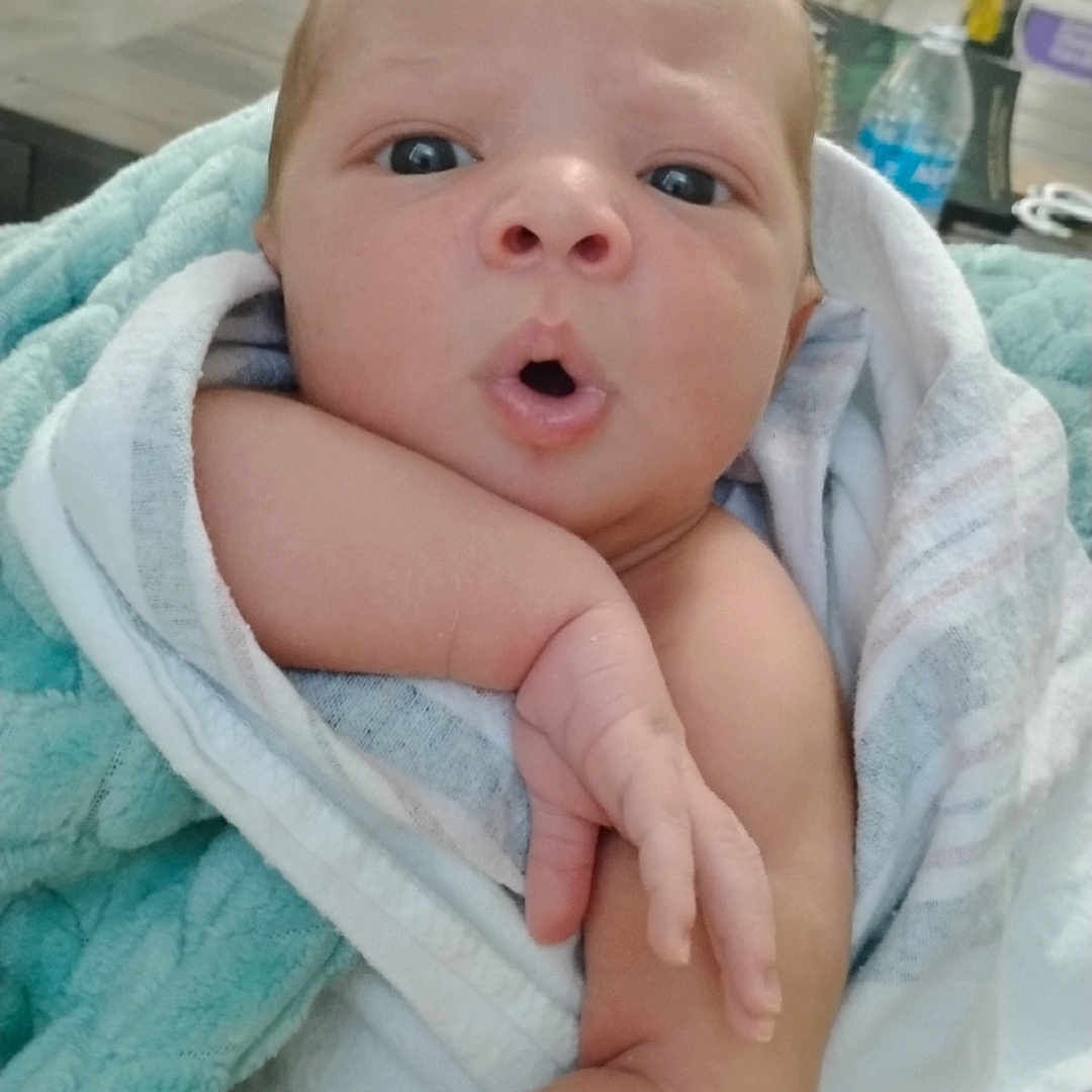 Kylon joined the competition — help win amazing prizes! baby, blanket, blurred_background, child, curious, cute, expression, face, furniture, hand, home, indoors, infant, newborn, person, portrait, skin, soft_texture, towel, wrapped