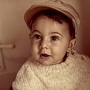 Sohan a rejoint le concours — aidez-le/la à gagner de superbes lots ! baby, child, face, hat, knitted_sweater, portrait, curious, wide_eyes, sepia, vintage, cozy, cute, indoor, infant, person, headwear, young_child, warm_tones, expression, closeup