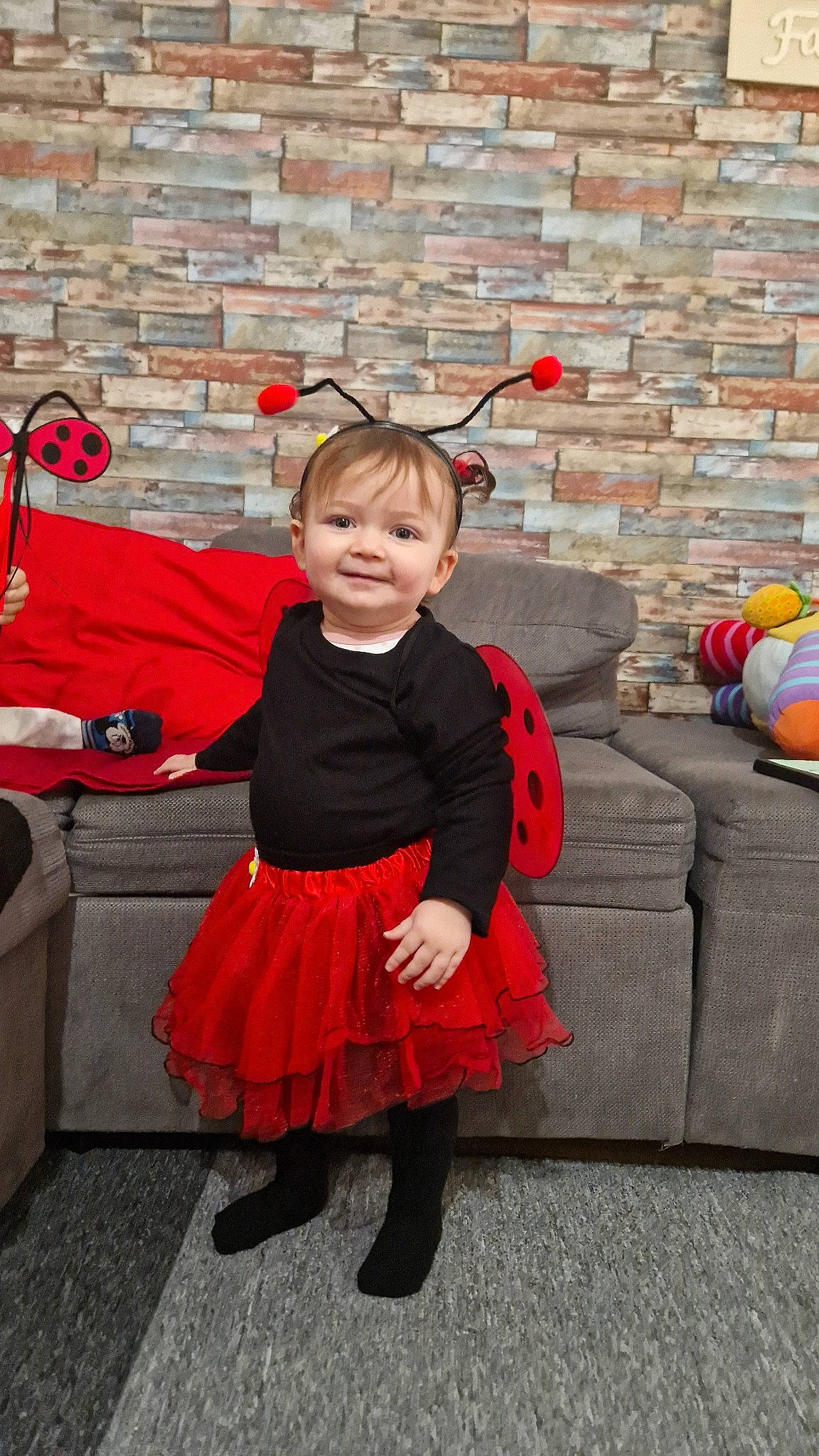 Mia participe au concours pour gagner de l'argent avec cette photo : baby_toddler_clothing, brick, brickwork, child, costume, event, facial_expression, fashion_accessory, fun, happy, joy, luggage_and_bags, magenta, orange, pattern, person, pink, recreation, sitting, smile