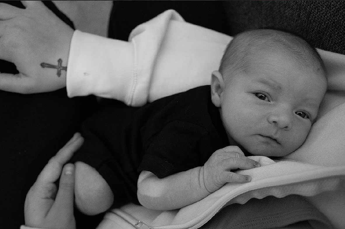 Sutton joined the competition — help win amazing prizes! baby, infant, person, hand, black_and_white, clothing, resting, portrait, newborn, sleepy, cuddle, comfort, close_up, soft_texture, human_skin, casual_wear, peaceful, indoor, holding, face