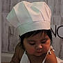 toddler, child, chef_hat, apron, flour, face, portrait, indoors, cute, cooking, baby, hat, kitchen, food, young_child, person, black_hair, expression, looking_down, skin