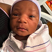 Kason joined the competition — help win amazing prizes! baby, newborn, infant, child, portrait, face, eyes, hat, beanie, blanket, swaddled, wrapped, sleepwear, indoor, cozy, closeup, looking_at_camera, brown_skin, seated, photography
