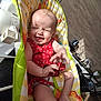 baby, child, infant, red_dress, laughing, smiling, baby_seat, colorful, lion_design, sunlight, indoor, happy, cute, hands, legs, diaper, home, floor, wall, window