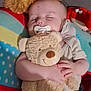 baby, sleeping, teddy_bear, pacifier, blanket, polka_dot, couch, soft_toy, child, cute, infant, smiling_toy, hand, resting, cozy, indoor, relaxed, comfort, head, clothing