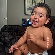 Kash joined the competition — help win amazing prizes! arm, baby, bed, black_bedspread, bridge_art, candid, child, diaper, door, face, hair, hand, happy, indoor, laughing, leg, picture_frame, skin, smiling, wall