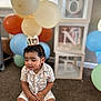 Kash is registered to the contest to win money with this photo: balloons, birthday, blocks, carpet, celebration, child, colorful, crown, cute, decor, floral_outfit, happy, headwear, indoor, one, party, sitting, smiling, toddler, young_child