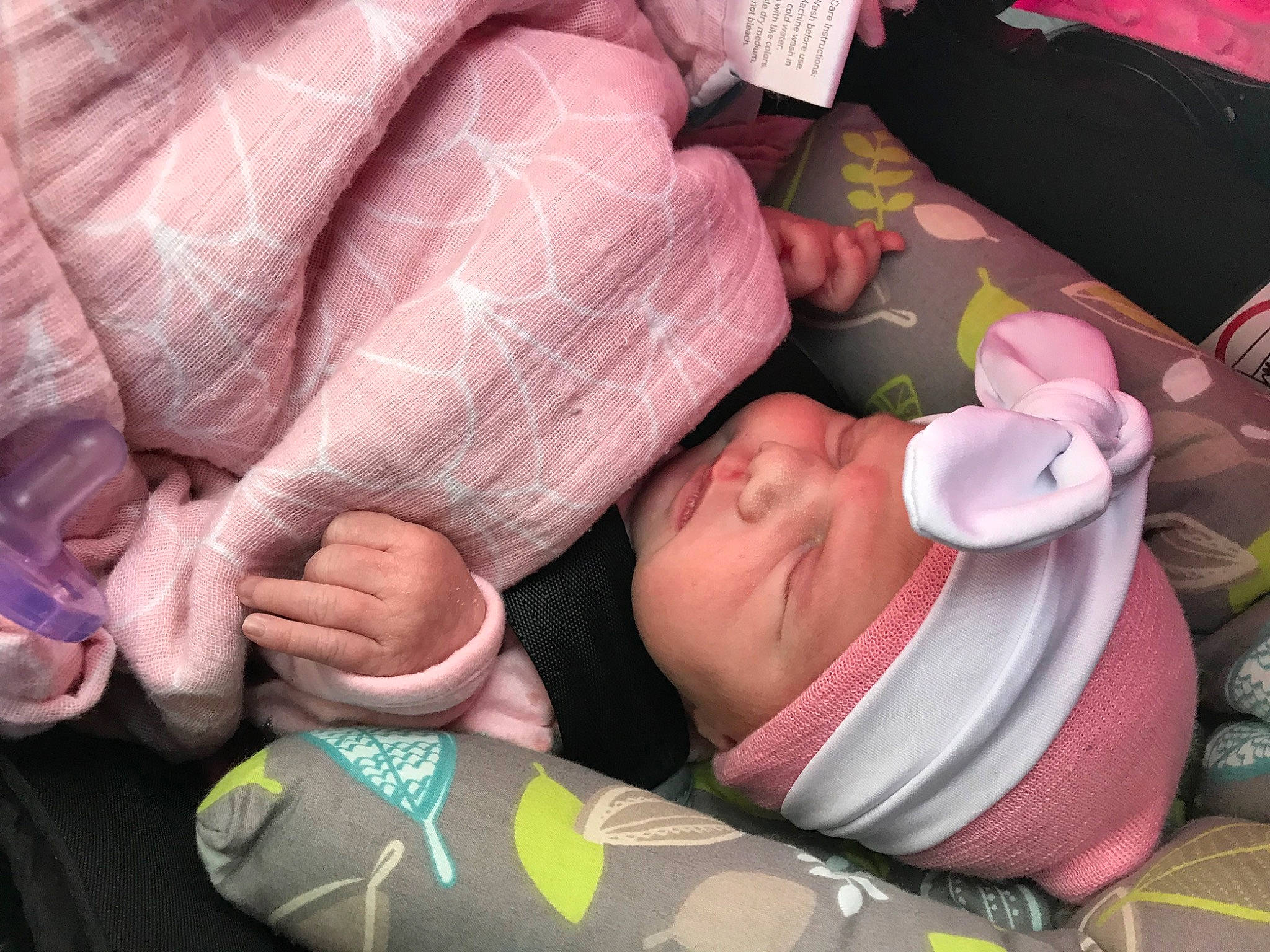 Naomi is registered to the contest to win money with this photo: baby, car_seat, cheek, child, comfort, drinkware, finger, gesture, glasses, headwear, human_body, leg, linens, mammal, mouth, nail, person, pink, skin, sunglasses