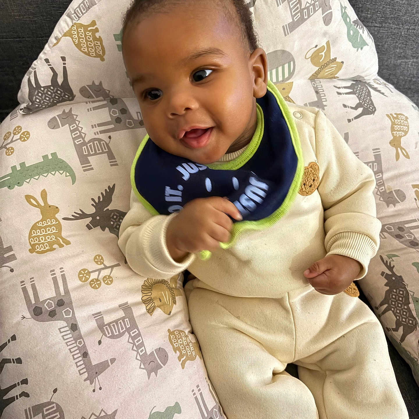 Sibani is registered to the contest to win money with this photo: baby, infant, child, smiling, sitting, bib, clothing, cushion, animal_print, fabric, cozy, indoors, portrait, cute, happy, face, person, furniture, soft_toys, relaxed