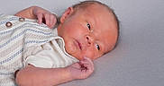 Carter is registered to the contest to win money with this photo: baby, clothing, cute, expression, eyes, face, hand, head, human, infant, lying_down, newborn, peaceful, portrait, resting, skin, small, soft_surface, striped_outfit, young