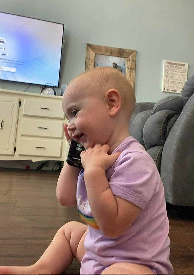 Guinevere is registered to the contest to win money with this photo: baby, cabinetry, comfort, drawer, floor, flooring, fun, happy, head, joint, knee, leg, person, picture_frame, room, sitting, smile, television, thigh, thumb