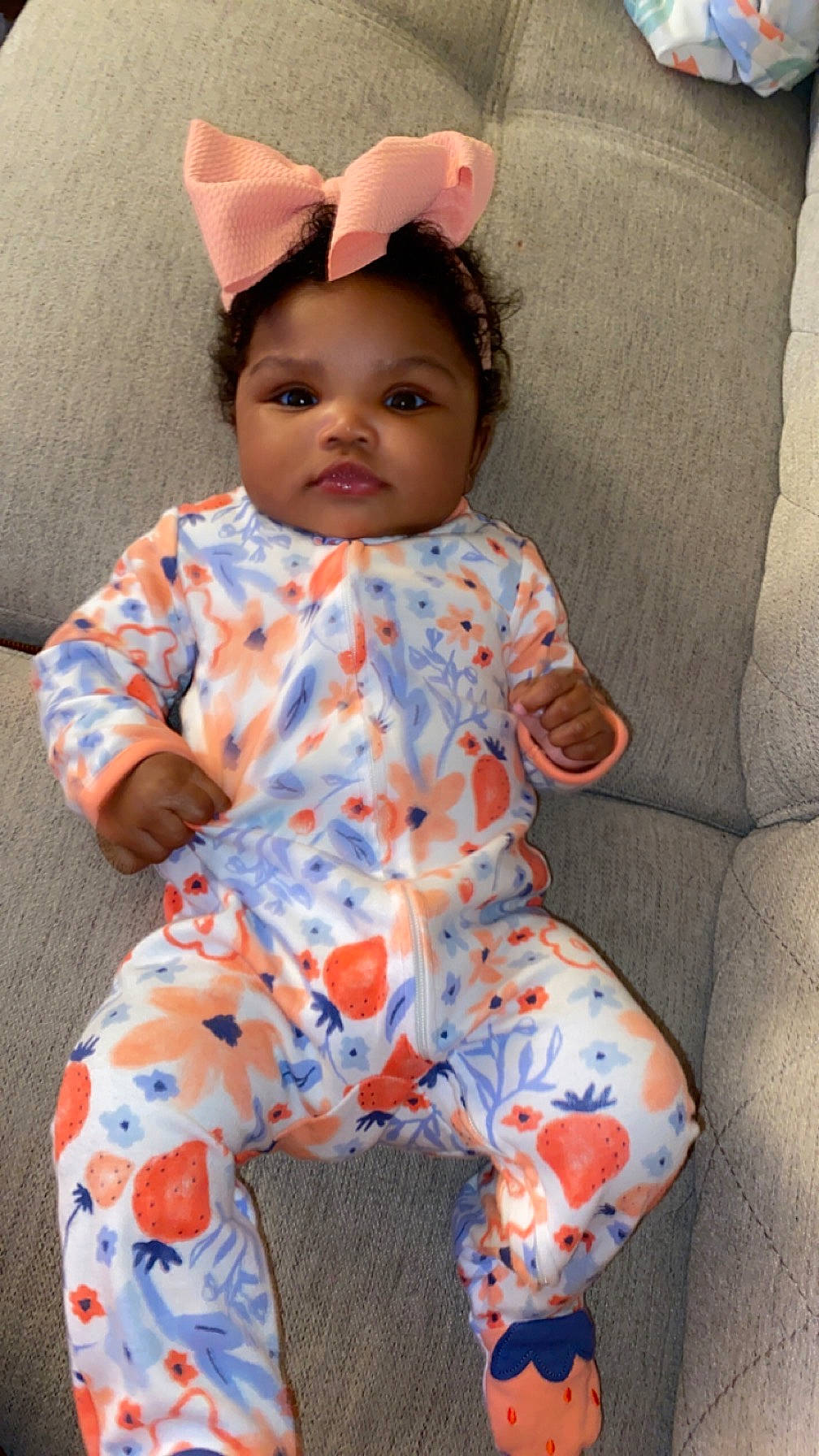 Gianna is registered to the contest to win money with this photo: baby, baby_toddler_clothing, cheek, child, collar, comfort, happy, human_body, linens, orange, pattern, peach, person, pink, sitting, skin, sleeve, t_shirt, textile, toddler