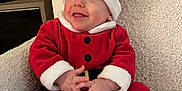 Gabriel Archilla participe au concours pour gagner de l'argent avec cette photo : baby, child, santa_claus_costume, red_clothing, white_fur_trim, hat, chair, smiling, happy, indoors, cute, holiday, christmas, festive, portrait, seated, cozy, plush, infant, person