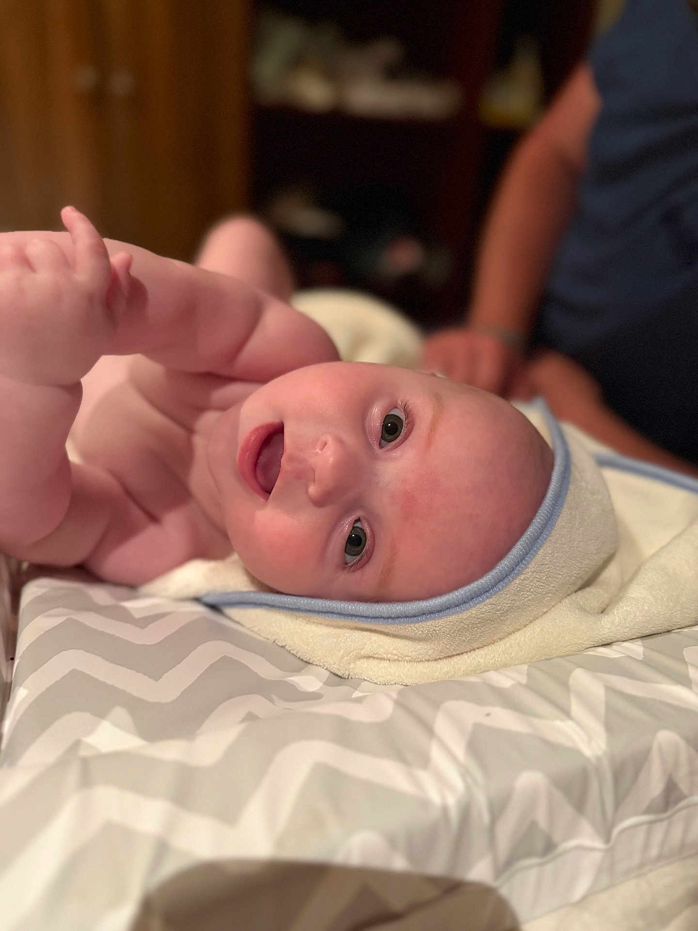 Oliver joined the competition — help win amazing prizes! baby, infant, towel, changing_pad, pattern, person, skin, face, eyes, expression, adult, blurred_background, indoor, soft_lighting, curious, chubby, cute, lying_down, hand, head