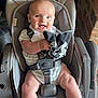 baby, car_seat, smiling, child, infant, happy, person, seatbelt, clothing, indoor, fabric, arm, leg, head, holding, toy, cute, face, furniture, safety