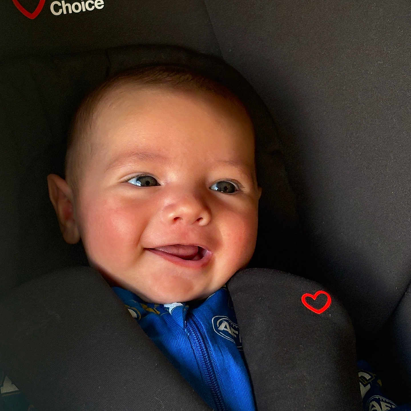 Rivah is registered to the contest to win money with this photo: baby, child, infant, car_seat, harness, portrait, close_up, smiling, tongue_out, face, eyes, blue_clothing, indoor, vehicle, safety, seated, happy, cute, photography, family