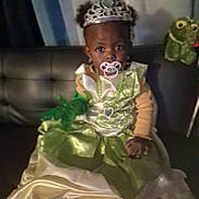Reijanae is registered to the contest to win money with this photo: child, dress, tiara, pacifier, green_dress, couch, indoor, toy, stuffed_animal, frog, jewelry, necklace, gloves, portrait, baby, sitting, curious, costume, cute, young