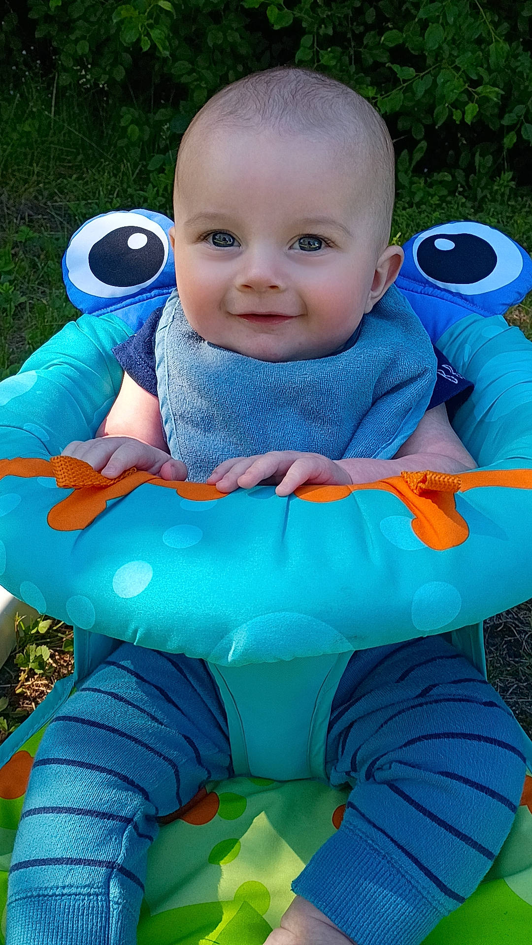 Milo joined the competition — help win amazing prizes! baby, baby_seat, blue_clothing, child, cute, face, grass, greenery, hands, happy, infant, nature, outdoor, playful, portrait, seat, smiling, striped_pants, sunlight, young_child