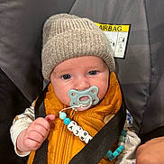 Charly a rejoint le concours — aidez-le/la à gagner de superbes lots ! baby, infant, pacifier, hat, vest, car_seat, seatbelt, child, cute, blue_eyes, clothing, person, sitting, indoor, safety, accessory, knit_hat, beads, closeup, portrait