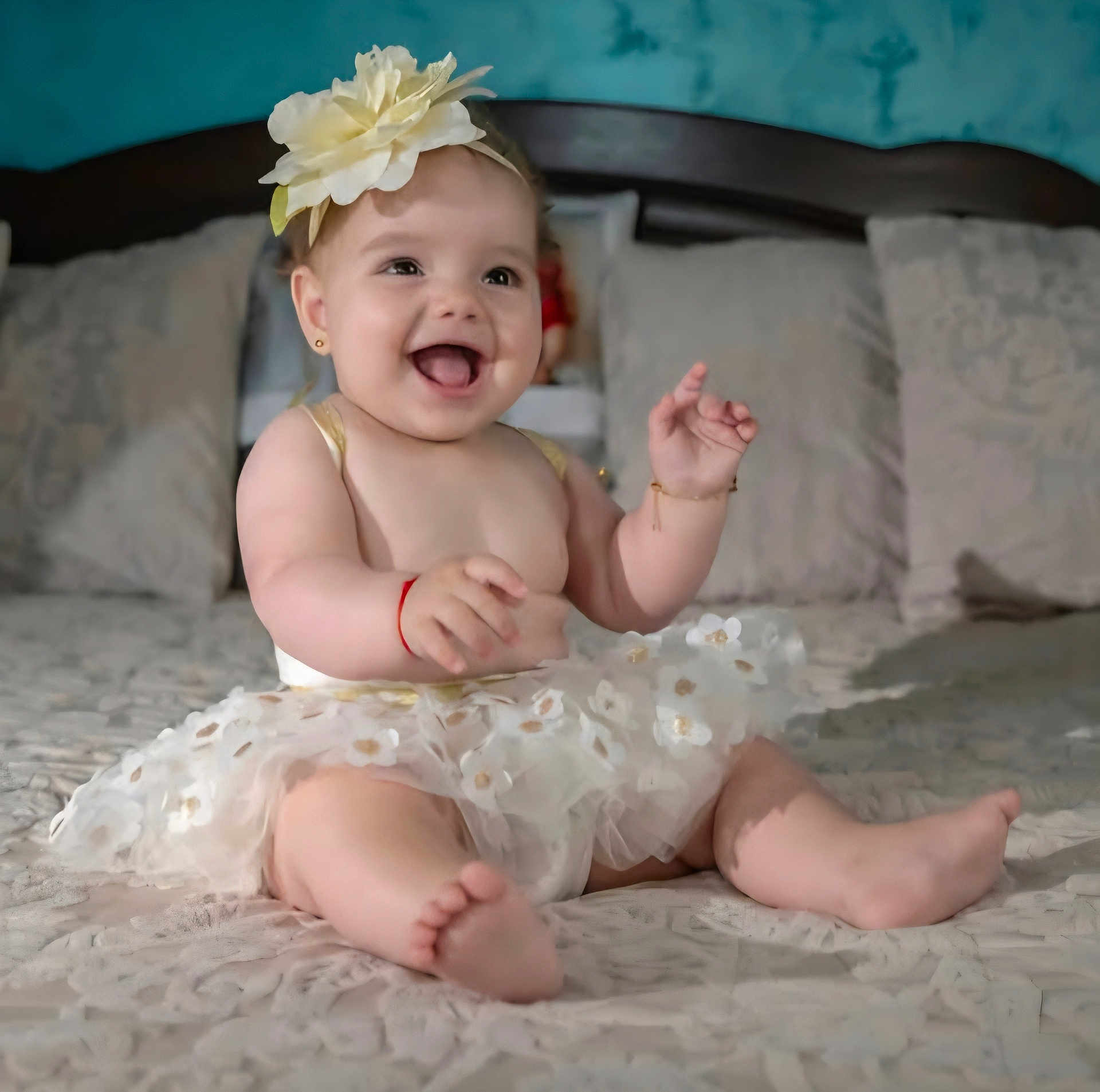Sofia is registered to the contest to win money with this photo: baby, child, flower_headband, tutu, smiling, happy, sitting, bed, pillow, blanket, indoors, cute, infant, joyful, apparel, skin, foot, hand, headwear, portrait