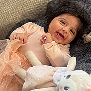 Kamilia-Nour participe au concours pour gagner de l'argent avec cette photo : baby, cheerful, child, couch, cozy, cute, dark_hair, dress, fabric, happy, indoor, infant, person, pink, playful, plush_toy, relaxing, smile, soft_toy, toddler