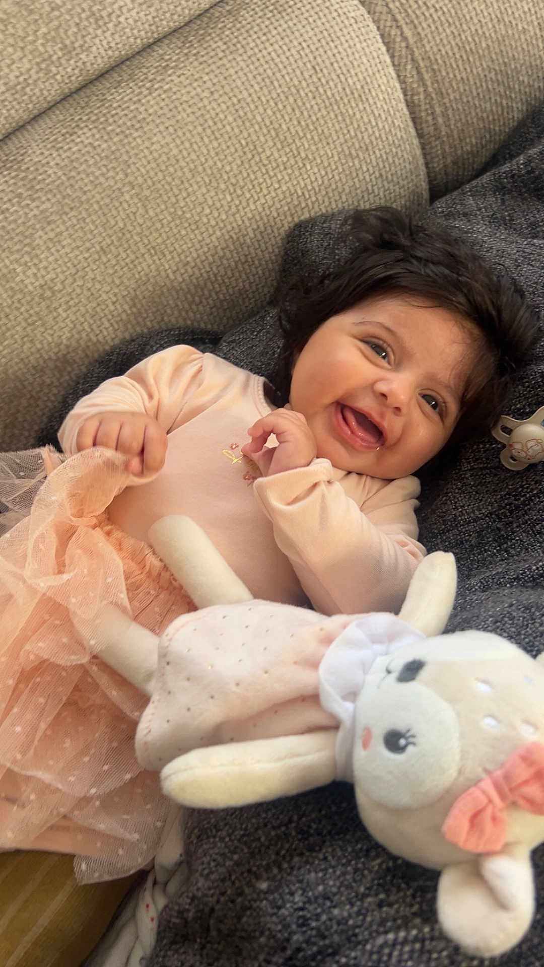 Kamilia-Nour participe au concours pour gagner de l'argent avec cette photo : baby, cheerful, child, couch, cozy, cute, dark_hair, dress, fabric, happy, indoor, infant, person, pink, playful, plush_toy, relaxing, smile, soft_toy, toddler