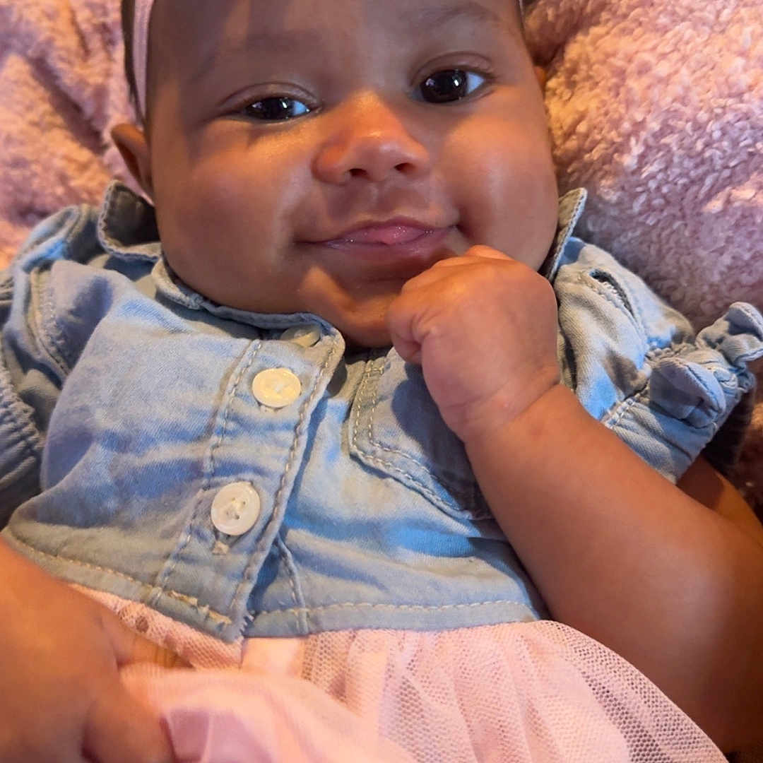 De'Lysia is registered to the contest to win money with this photo: baby, blanket, bow, child, clothing, cozy, cute, denim_jacket, face, hand, happy, headband, indoors, infant, pink, portrait, smiling, soft_texture, tulle_skirt, young