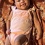 baby, infant, smiling, lying_down, peach_outfit, patterned_blanket, orange, cream, cute, happy, child, portrait, skin, face, arms, legs, young, one_person, indoors, fabric