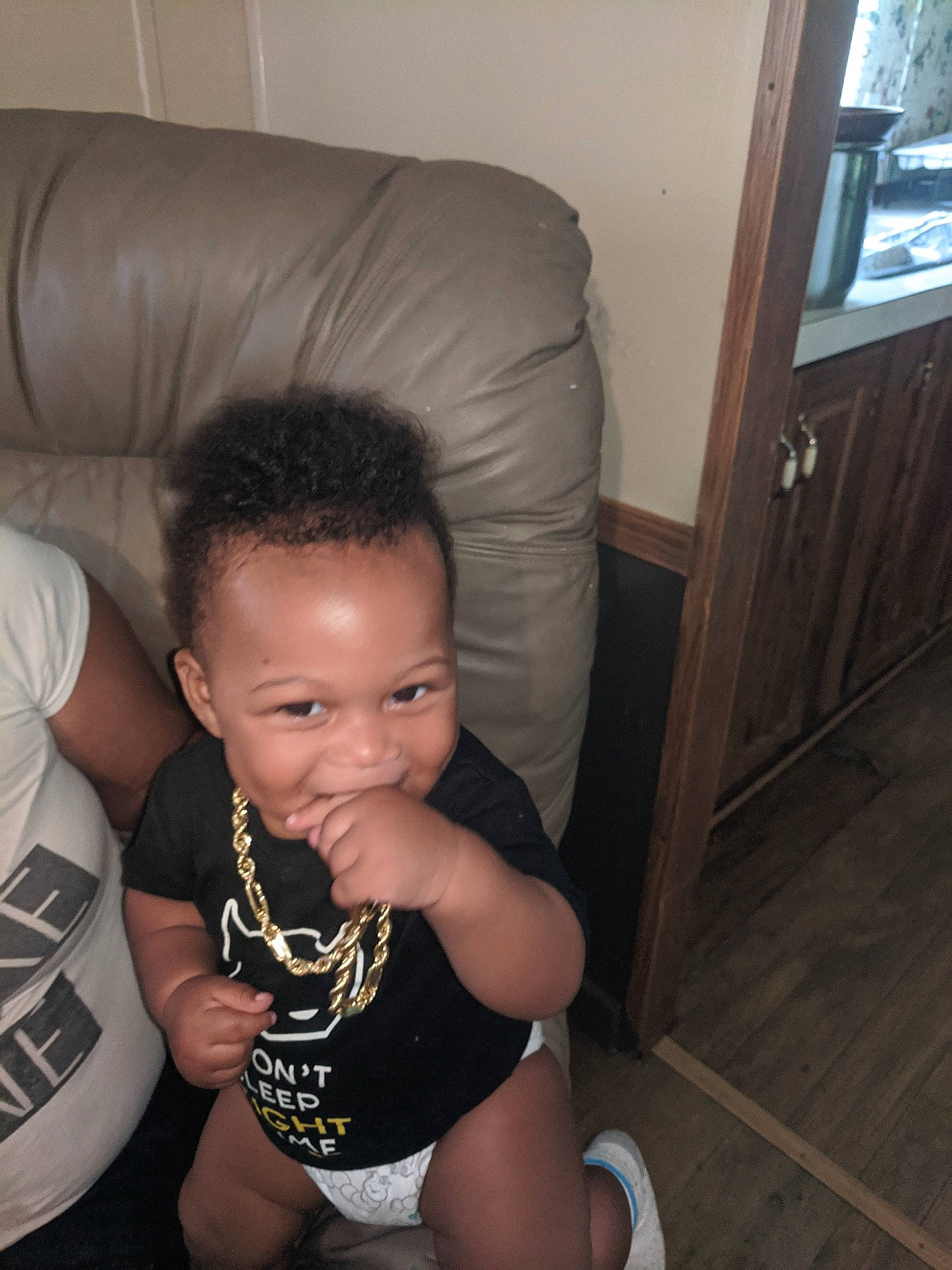 Jabari is registered to the contest to win money with this photo: arm, baby, chair, chest, comfort, finger, flash_photography, floor, flooring, hairstyle, joy, leg, mouth, neck, person, shoulder, skin, smile, standing, television