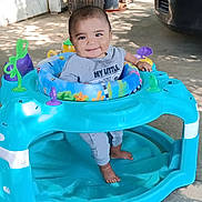 Jesse is registered to the contest to win money with this photo: baby, walker, smile, outdoor, child, toy, foot, plant, concrete, play, happy, clothing, person, seat, sunlight, shadow, face, blue, green, purple