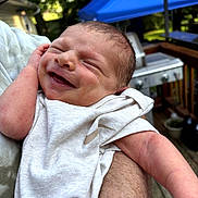 Gavin is registered to the contest to win money with this photo: arm, baby, blue, canopy, closeup, daylight, expression, hand, happy, head, infant, nature, newborn, outdoor, parent, person, portrait, skin, smile, white_clothing