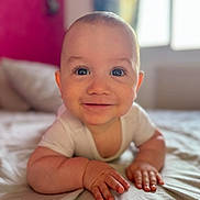 Marceau participe au concours pour gagner de l'argent avec cette photo : baby, infant, smile, face, eyes, arms, bed, blanket, white_clothing, indoors, window, natural_light, skin, cute, child, person, happy, young, head, lying_down