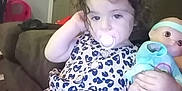 Elizabeth joined the competition — help win amazing prizes! toddler, child, pacifier, doll, dress, curly_hair, couch, indoor, toy, brown_couch, patterned_dress, relaxed, young_child, furniture, home, person, cute, baby_doll, seated, casual