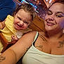 toddler, child, woman, smiling, tattoos, piercings, yellow_dress, wooden_interior, restaurant, television, neon_sign, happy, casual, indoor, person, face, hair, clothing, seat, table