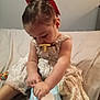 toddler, child, baby_wipes, pacifier, red_bow, dress, sitting, bed, blanket, indoors, person, baby, cute, hands, clothing, toy, face, skin, hair, focus