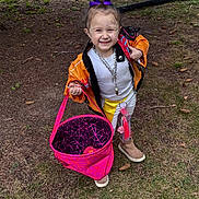 Laylani joined the competition — help win amazing prizes! child, smiling, face_paint, purple_bow, orange_jacket, white_pants, boots, pink_bag, outdoor, grass, pinecones, sidewalk, car, chain_necklace, happy, person, playful, accessory, fashion, cute