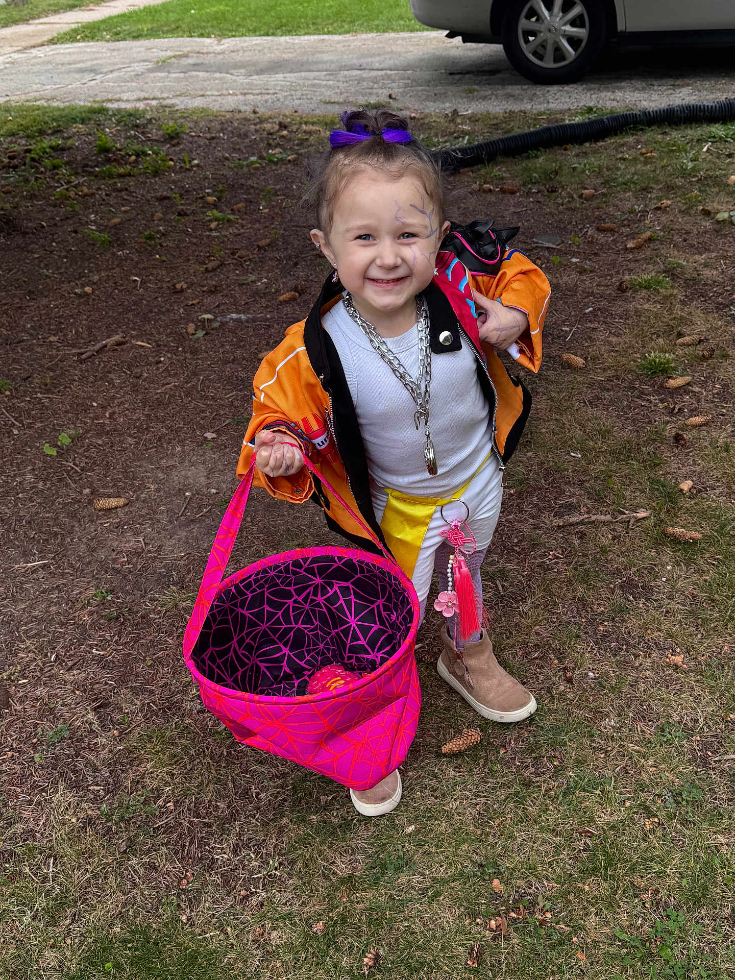 Laylani joined the competition — help win amazing prizes! child, smiling, face_paint, purple_bow, orange_jacket, white_pants, boots, pink_bag, outdoor, grass, pinecones, sidewalk, car, chain_necklace, happy, person, playful, accessory, fashion, cute