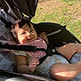Arabelle is registered to the contest to win money with this photo: baby, child, stroller, pink_bib, smiling, sunlight, grass, outdoor, safety_strap, infant, happy, cute, person, seat, clothing, head, hand, leg, daylight, relaxing