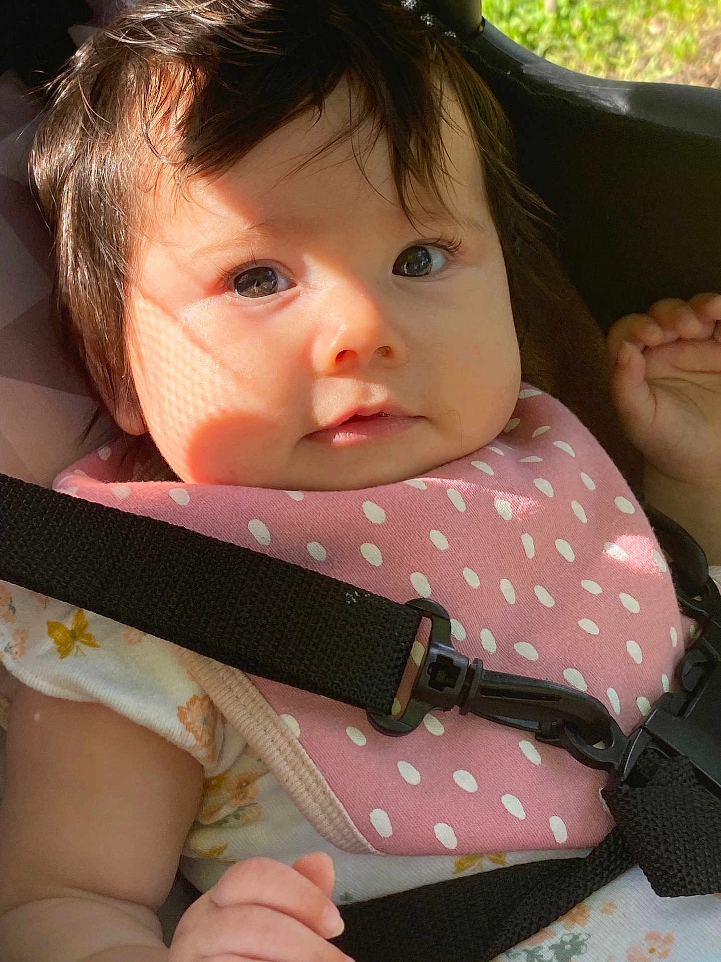 Arabelle joined the competition — help win amazing prizes! baby, child, face, eyes, pink_bib, polka_dots, car_seat, black_strap, sunlight, shadow, curly_hair, cute, infant, close_up, clothing, sitting, skin, hand, expression, adorable