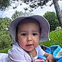 baby, child, hat, white_clothing, blanket, grass, outdoor, trees, nature, sky, greenery, portrait, infant, cute, sunhat, relaxing, daytime, person, closeup, park